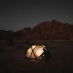 Solo Destination - a person sitting inside of a tent in the desert