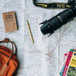 Slow Travel - flat lay photography of camera, book, and bag