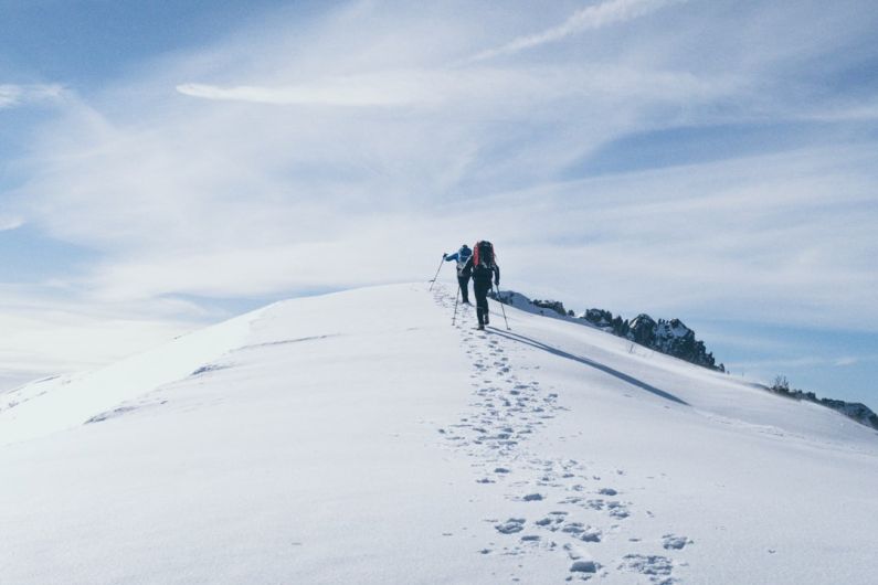 Mountain Climbing - two person climbing on mountain covered snow